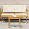 A wooden bench and coffee table set with cream cushions, placed on a stone patio in front of a wooden wall. Voir les images du produit