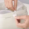 A close-up shot of hands interacting with a white trash can, specifically tucking in a plastic liner. Voir les images du produit