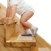A baby is climbing up wooden stairs with anti-slip mats on the steps. Produktbild-Vorschau