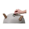 A hand is shown inserting a black plug into a hole on the top of a gray planter pot with brown legs. Náhľad obrázku produktu