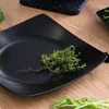 A black square plate with a sprig of thyme on it, set on a wooden surface. Náhled obrázku produktu