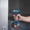 A hand holding a Bosch cordless drill and drilling into a white surface. Voir les images du produit