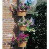 Three hanging planters with flowers attached to a downspout against a brick wall. Podgląd zdjęcia produktu