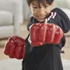 A young boy wearing large red Hulk-like gloves and a black hoodie is posing for the camera with a determined expression. Anteprima dell’immagine prodotto