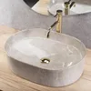 A close-up view of a marble-patterned vessel sink with a gold faucet. Podgląd zdjęcia produktu