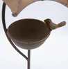 A close-up view of a metal bird feeder with a decorative bird attached. Voir les images du produit