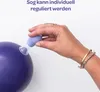 A hand is holding a breast pump accessory against a large purple ball. Náhled obrázku produktu