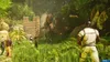 A group of people in a jungle setting are looking at a dinosaur that is breaking through a wooden structure. Produktbild-Vorschau