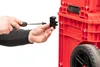 A person is using a screwdriver to attach a black connector piece to a red Qbrick tool box. Produktbild-Vorschau