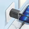 A black Hoco N42 GaN 45W USB QC 3.0 charger is plugged into a white wall socket and charging a smartphone. Produktbild-Vorschau