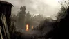 A dark, atmospheric scene of a village with burning structures and smoke. Produktbild-Vorschau