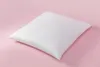 A white pillow is placed on a pink background. Produktbild-Vorschau