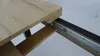 Close-up view of an extendable table mechanism, showing the wooden tabletop and metal sliding rails. Náhled obrázku produktu