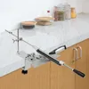 A knife sharpening system is clamped to a kitchen counter, with jars of spices in the background. Náhled obrázku produktu