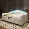 A modern white daybed with blue LED lighting is displayed in a room with a large window and rug. Náhled obrázku produktu