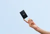 A hand holding a small black external hard drive against a light blue background. Náhľad obrázku produktu
