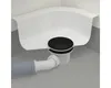 A close-up view of a shower drain assembly connected to a pipe, installed in a white shower tray against a gray background. Anteprima dell’immagine prodotto