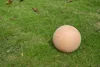A terracotta garden ball rests on a patch of green grass with scattered fallen leaves. Náhľad obrázku produktu