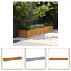 A long, wooden planter box filled with plants sits on a gravel path next to a dark fence. Náhľad obrázku produktu