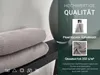 A stack of gray waffle-weave towels on a dark shelf next to a vase, with marketing text and close-up images of the product's features. Produktbild-Vorschau