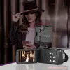 A woman in a hat is holding a phone and looking at it, with a camera and an attached light in the foreground. The camera screen shows a reflection of the woman. Náhled obrázku produktu