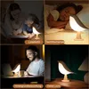 Collage of four scenes showing a bird-shaped lamp in different settings. Produktbild-Vorschau