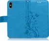 A blue flip case for a smartphone, decorated with embossed floral and butterfly patterns. Produktbild-Vorschau