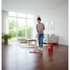 A woman is mopping a wooden floor in a bright, modern living room. Produktbild-Vorschau