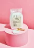 A bag of pyramid salt sits on a pink pedestal, with a small dish of salt and a wooden spoon in front of it. Produktbild-Vorschau