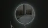 A circular LED mirror with a light ring is mounted on a dark wall. The mirror reflects a dimly lit interior. Voir les images du produit