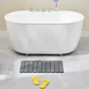 A white bathtub with a gray bath mat and yellow flip-flops in front of it. Anteprima dell’immagine prodotto