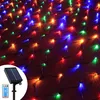 A close-up view of a net of colorful LED lights, with a solar panel and remote control in the bottom left corner. Produktbild-Vorschau