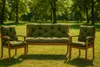 A garden bench and two chairs with green cushions are set up on a grassy lawn with trees in the background. Produktbild-Vorschau