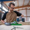 A man is using a Bosch cordless impact wrench to drill into a piece of wood, with screws in the foreground. Voir les images du produit