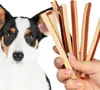 A dog looks at a hand holding dog treats. Produktbild-Vorschau