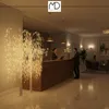 A hotel lobby with a reception desk and decorative trees. Podgląd zdjęcia produktu