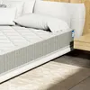 A close-up view of a mattress on a bed with pillows and a nightstand. Produktbild-Vorschau