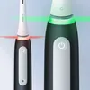 Close-up of two Oral-B iO 3 electric toothbrushes, one black and one white, with green and red light indicators. Voir les images du produit