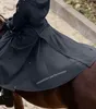 A person riding a horse, wearing a dark blue riding coat and a dark blue cape. Produktbild-Vorschau