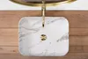A top-down view of a marble-patterned sink with a gold faucet, set against a wooden background. Produktbild-Vorschau