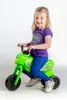 A young girl is sitting on a green toy motorcycle. Voir les images du produit