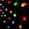 A string of colorful solar-powered LED lights with crystal-like bulbs, illuminating a dark outdoor setting, possibly a garden or balcony. Produktbild-Vorschau