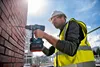 A construction worker is drilling into a brick wall with a cordless hammer drill. Anteprima dell’immagine prodotto