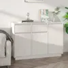 A white wooden sideboard with two drawers and three doors, placed in a room next to a sofa and a plant. Náhled obrázku produktu