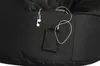 Close-up view of a black beanbag chair with a small pocket holding a smartphone and earbuds plugged into it. Produktbild-Vorschau