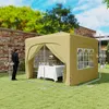 A beige pop-up gazebo set up on a grassy lawn with a table and chairs inside, with a man standing next to it. Podgląd zdjęcia produktu
