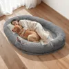 A woman and a dog are sleeping together on a large, plush dog bed. Voir les images du produit
