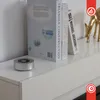 A silver cylindrical speaker sits on a white shelf next to two books and a golden deer figurine. Náhľad obrázku produktu