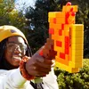 A person holding a Minecraft-themed NERF blaster outdoors. Podgląd zdjęcia produktu