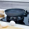 A frying pan on a stovetop with two eggs in the foreground. Náhľad obrázku produktu